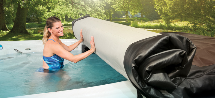 femme enroulant le système de couverture de l'axe à l'intérieur de son spa de nage