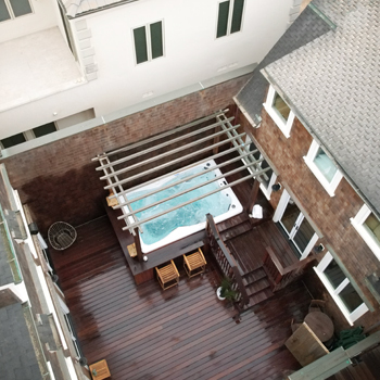 Un spa de nage installé dans un petit patio clôturé, au fond du jardin.