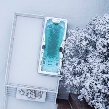 Vue prise par drone d'un spa de nage en fonctionnement en hiver, au milieu de la neige.