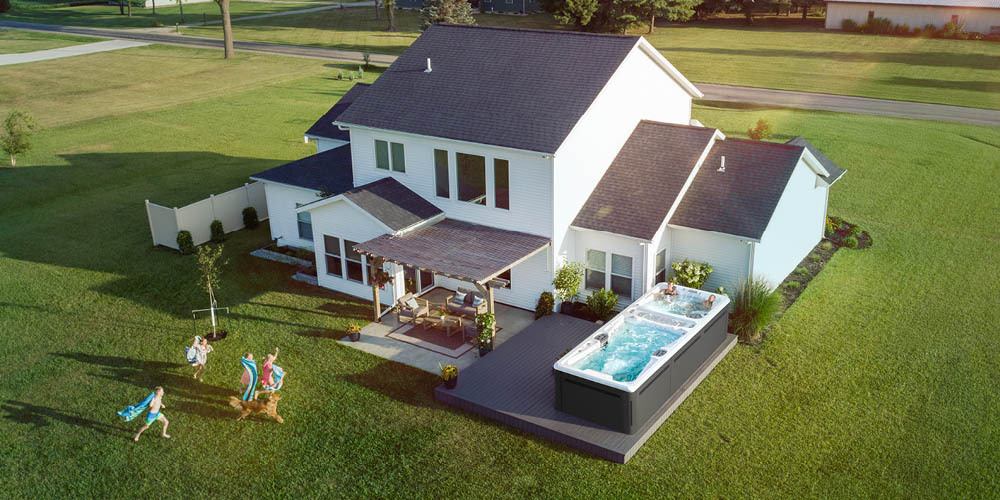 Vue prise par drone de l'arrière-cour d'une maison, où se trouve un spa de nage.