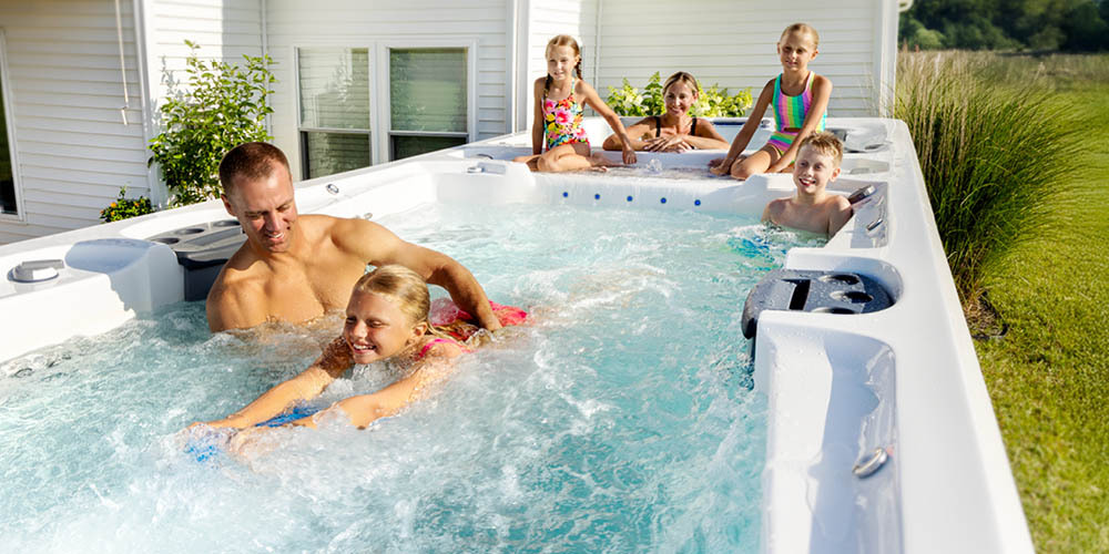 Une famille s'amuse dans un spa de nage et une fillette utilise une planche pour nager à contre-courant.